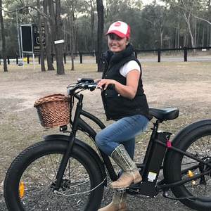 a woman riding a bike down a dirt road